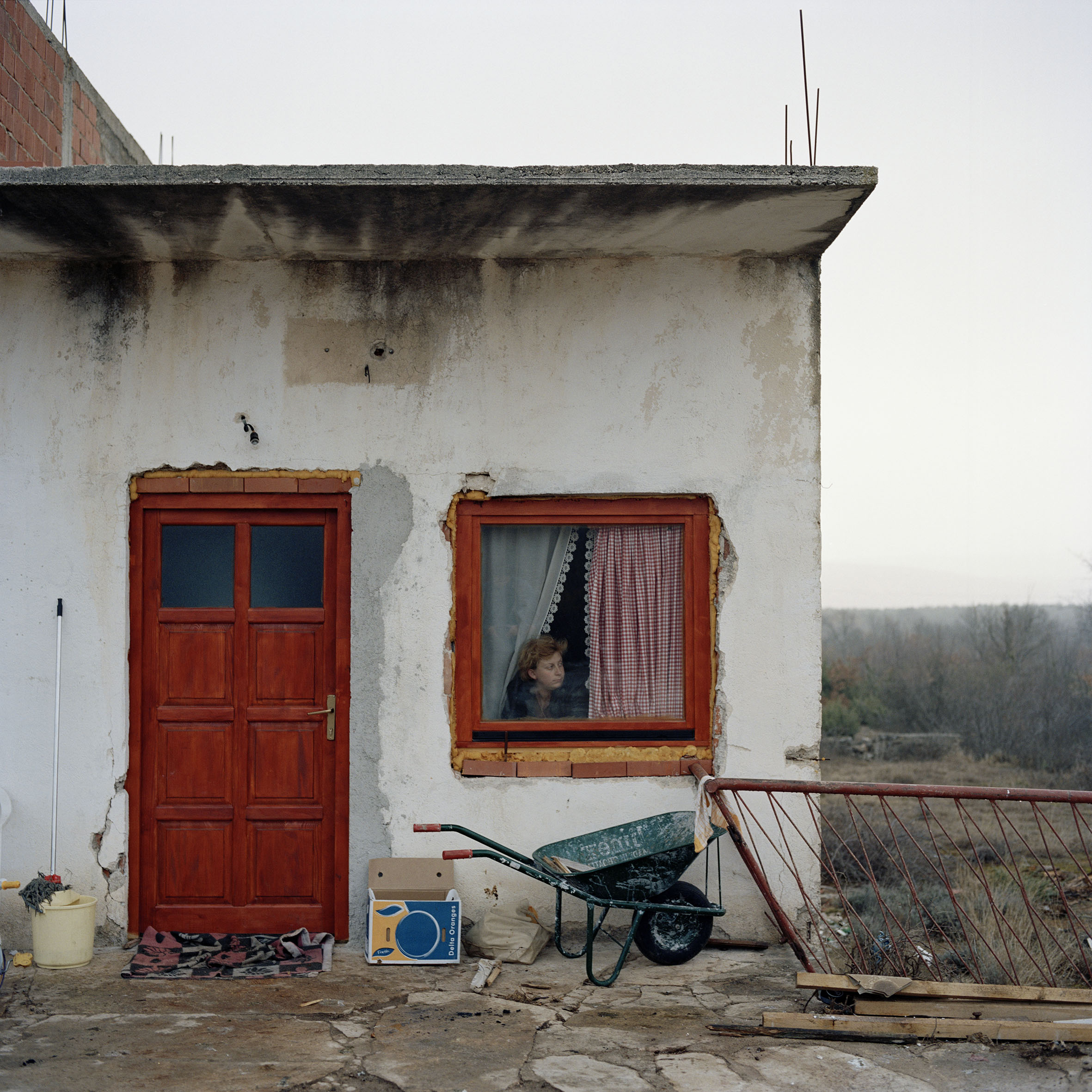  Jasna Calic looks out on the road from her kitchen window. The previous day while sitting in front of the house with her two young children a group of passing Croat youths shouted 'Fuck your Chetnik mother' at Jasna. This was the third racist incide