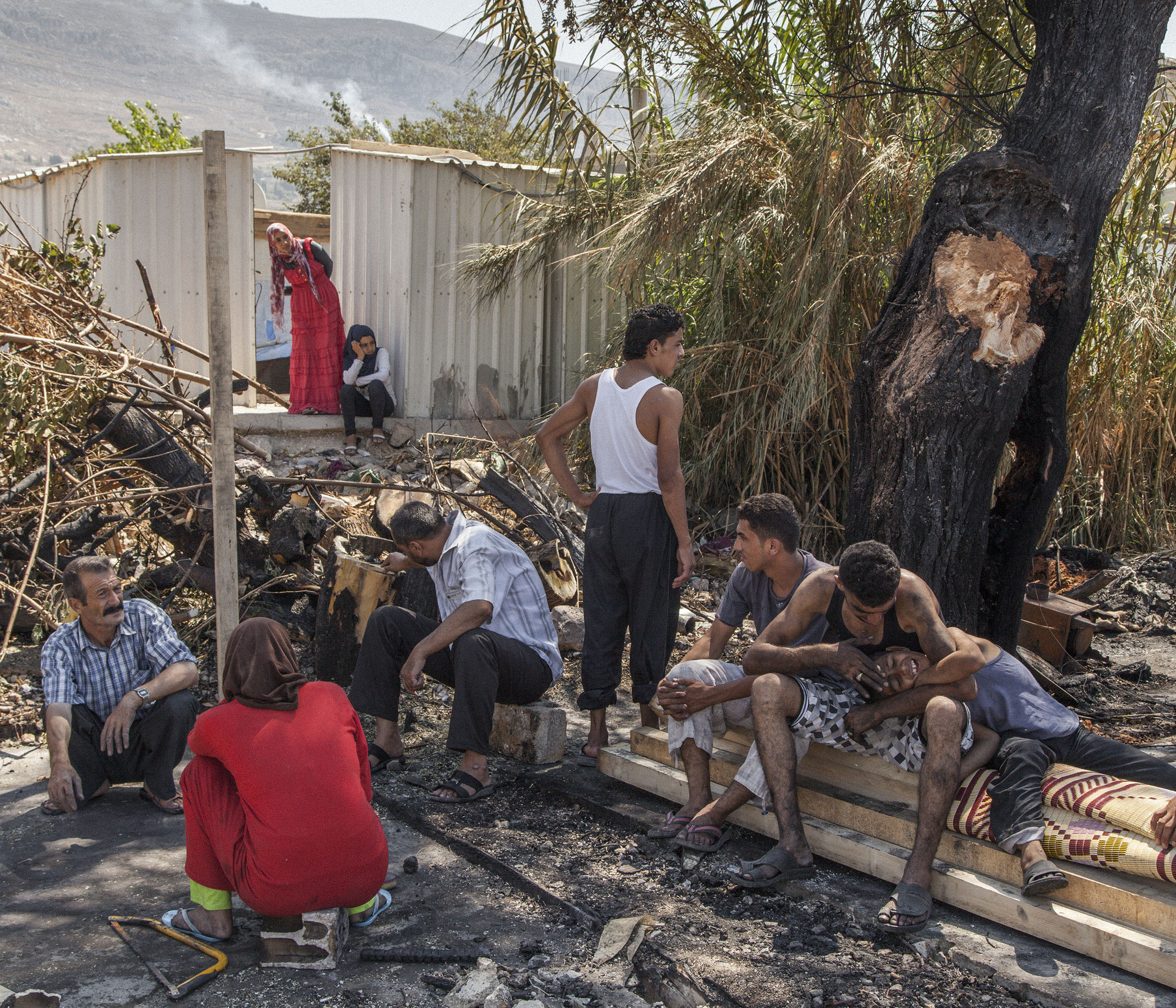  The Al-Rashid family, from Hama in Syria, sit amongst the ashes of their shelter. A fire the previous day destroyed all of the 25 tents that stood in the Al-Rashid camp on the outskirts of Minieh in Northern Lebanon, a town on the border with Syria.