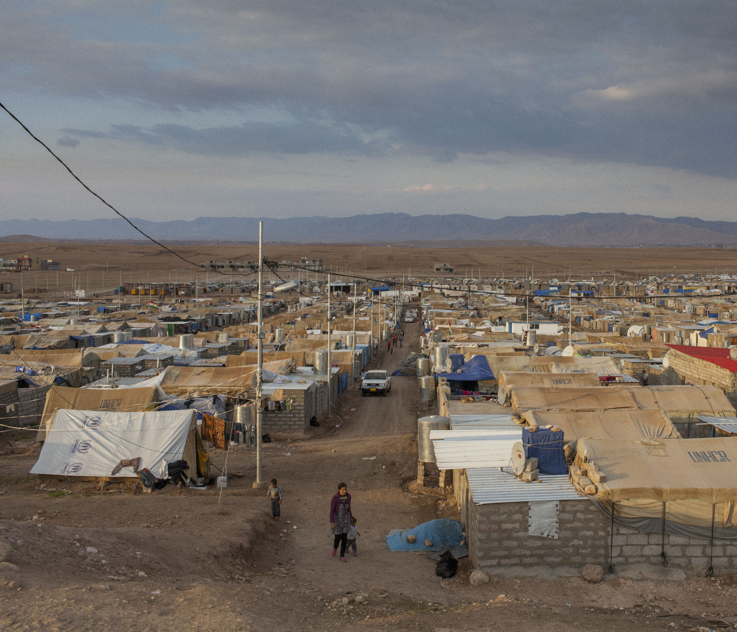  A Syrian woman and her child walk through Domiz Refugee Camp. 