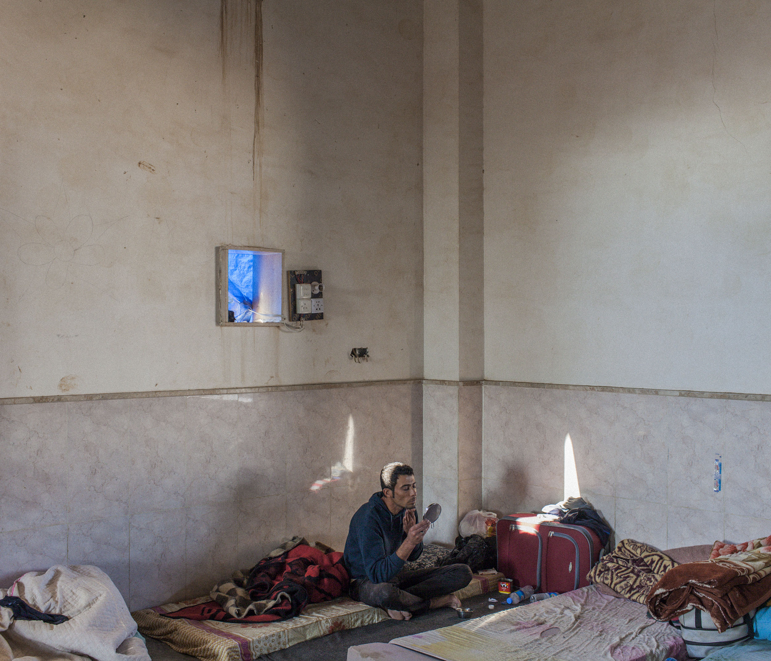  A young Syrian Kurdish refugee shaves in an unfinished mosque where up to 100 single men were living in squalid conditions in Domiz Refugee camp in Northern Iraq. With families and women being given priority, single un-accompanied men were last to b