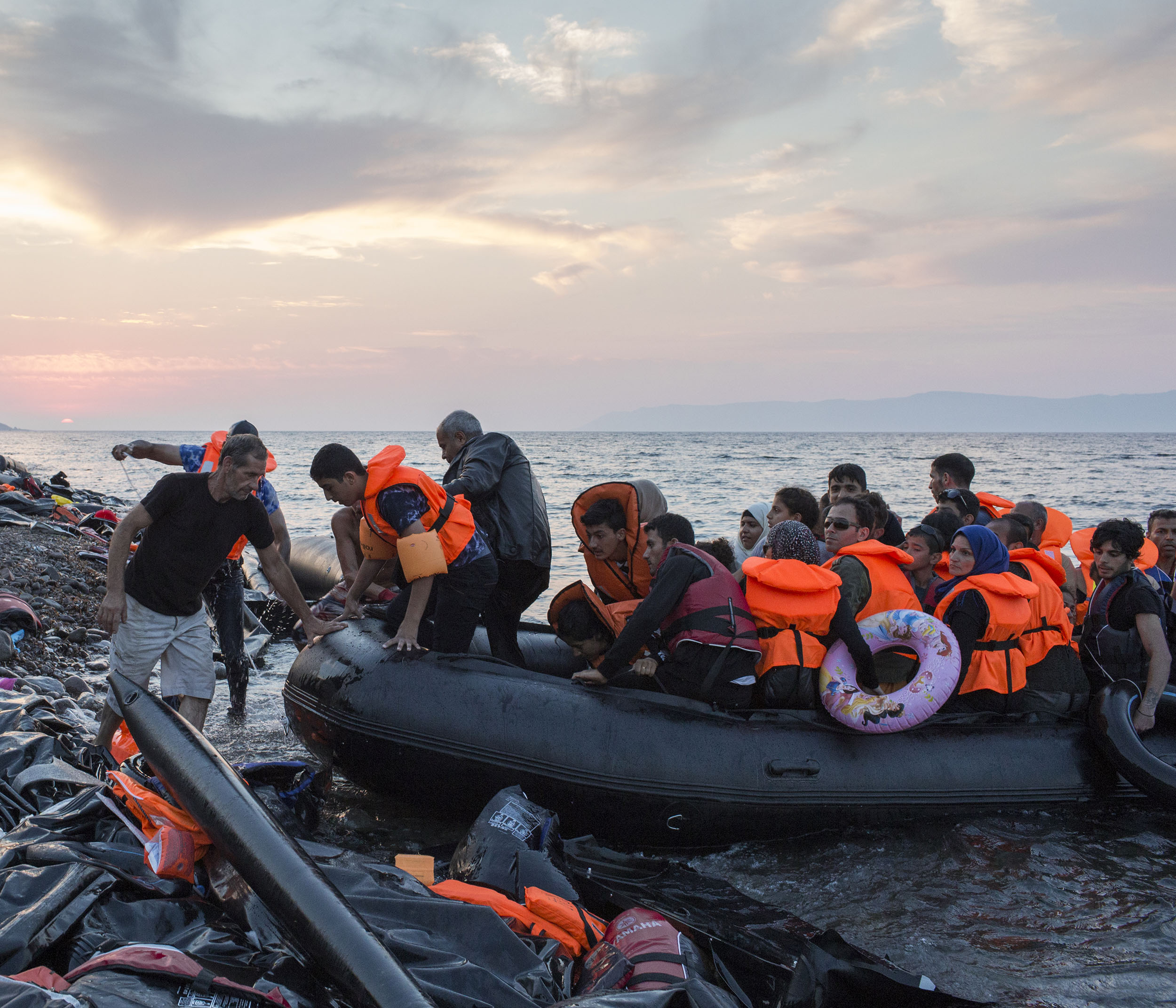 As the sun goes down a group of mainly Syrian refugees arrive on the Greek island of Lesbos having crossed the Aegean from Turkey.
