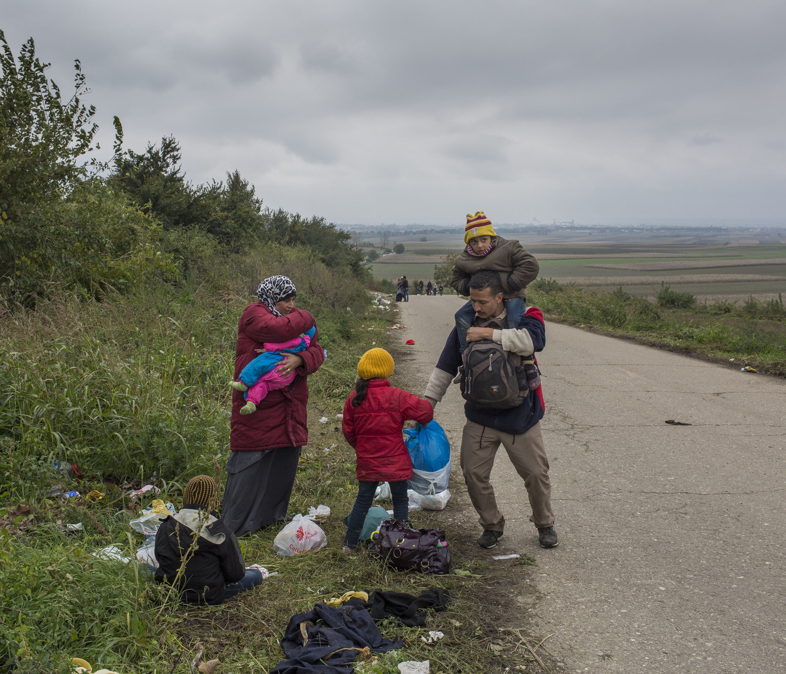 A family of Syrian refugees gather their belongings after a short rest on the side of the road as they walked the final stretch of the journey towards the border between Serbia and Croatia.