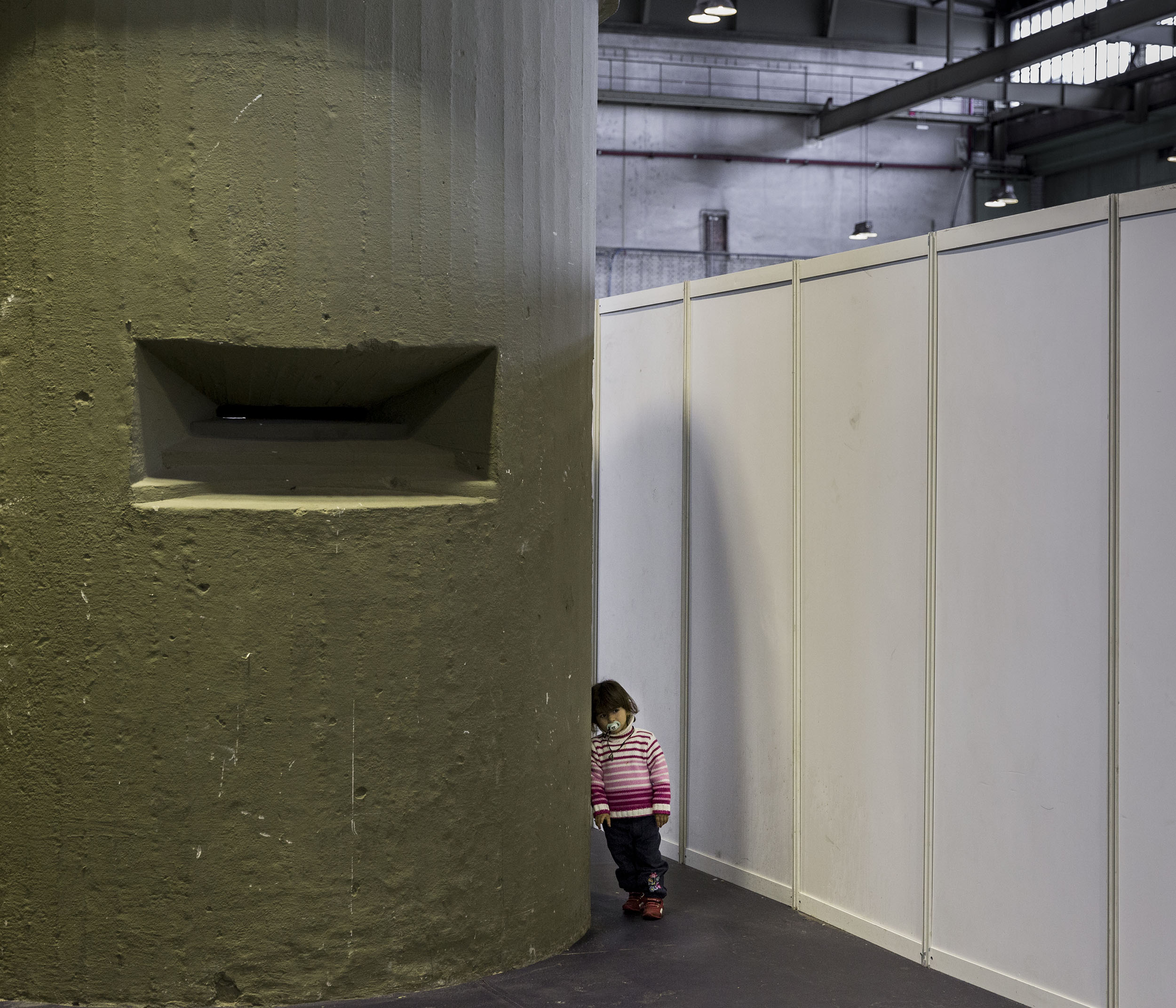A young Syrian refugee stands beside an old bunker inside a hangar at Tempelhof airport.