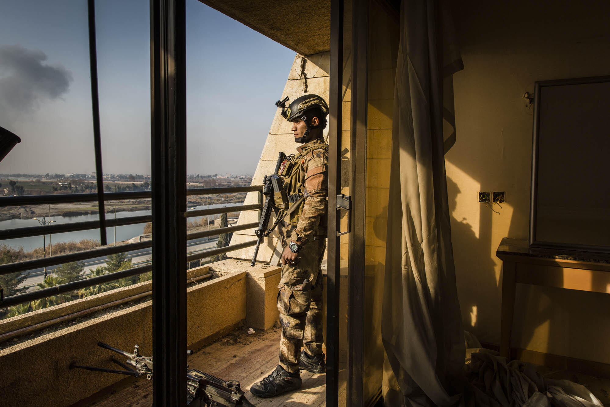  An Iraqi special forces soldier looked out over the river Tigris, towards ISIS controlled west Mosul from the balcony of a room at the Nineveh International Hotel. Iraq - January 2017 