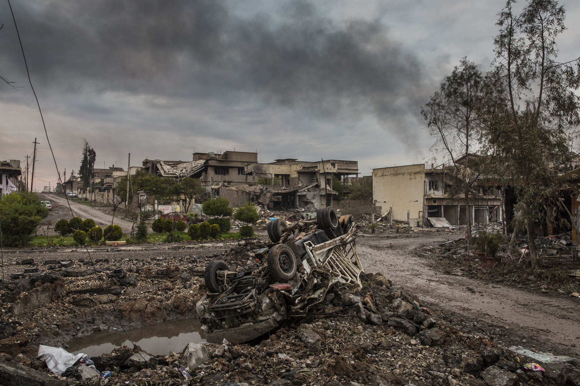  A bombed out vehicle lay beside a massive crater after fierce fighting between Iraqi special forces and ISIS militants in the Jadidah neighbourhood of west Mosul. Iraq - March 2017 