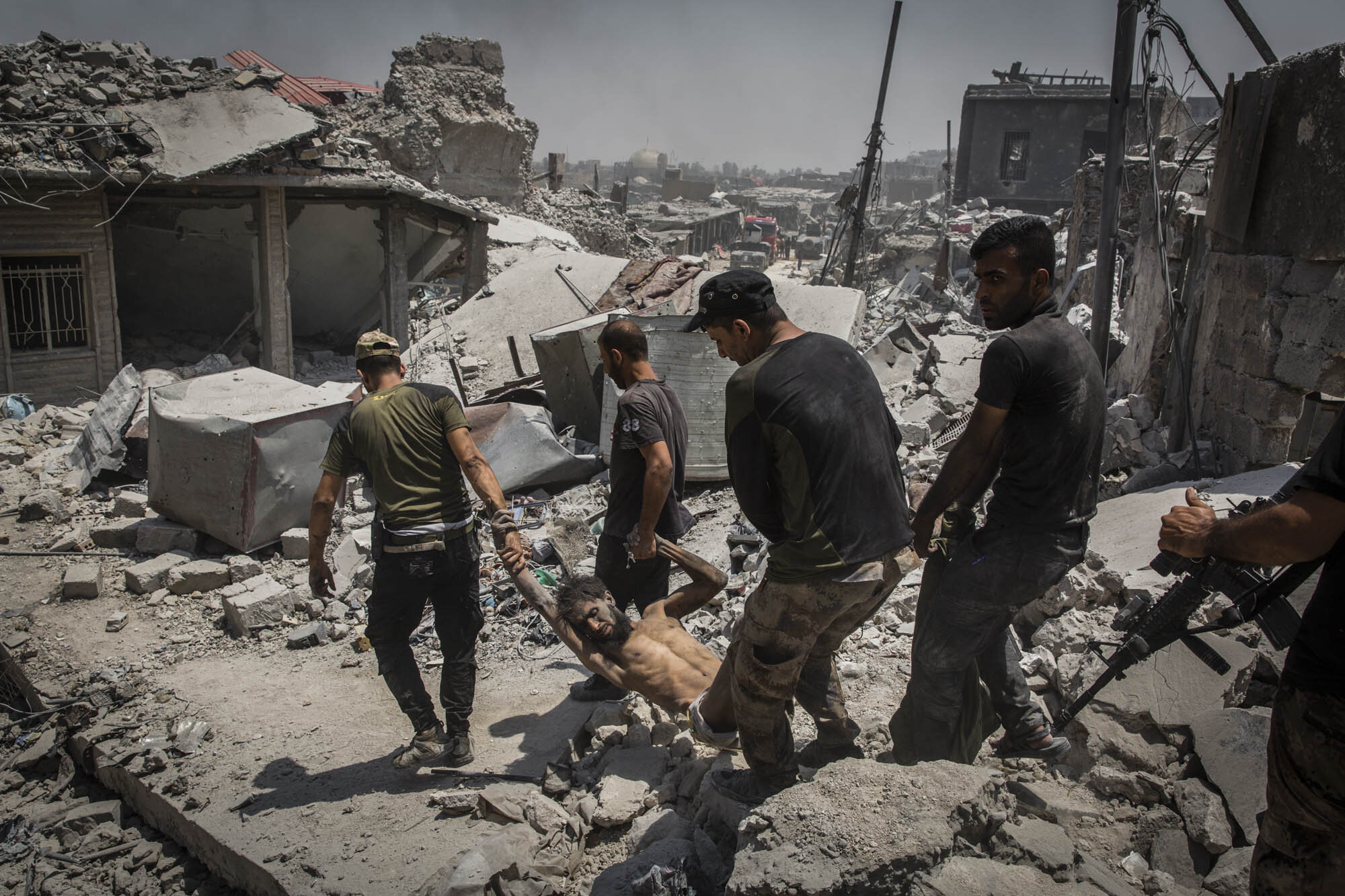  Iraqi special forces soldiers carried away an injured ISIS fighter who had surrendered, moments after they dragged him out of the basement of a destroyed building in the Maydan area of Mosul’s Old City. Iraq - July 2017 