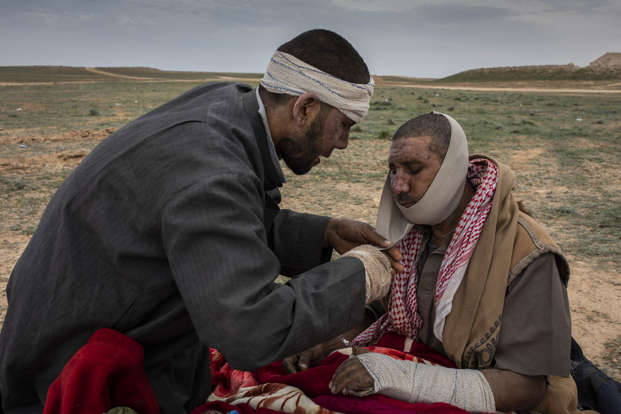  Abdulrahman Salam changed the dressing on his father Salam Abid's badly wounded face at a screening point for people who had fled the last ISIS controlled village in eastern Syria.  