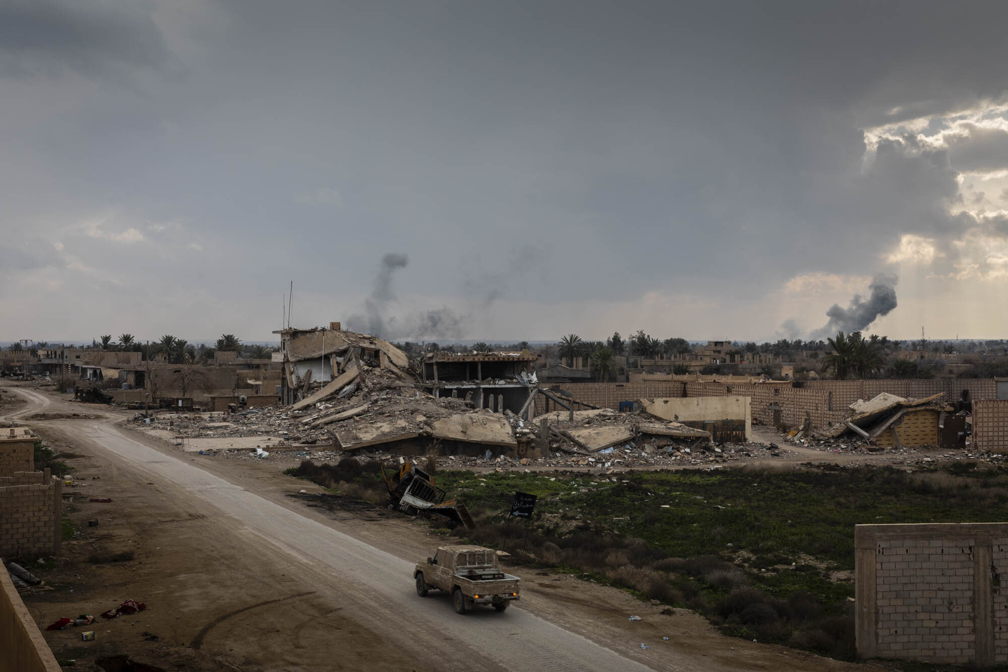  A Syrian Democratic Forces  (SDF) vehicle drove towards the frontline of fighting, during the final weeks of the operation to defeat ISIS, as plumes of smoke from artillery strikes rose in the distance.  