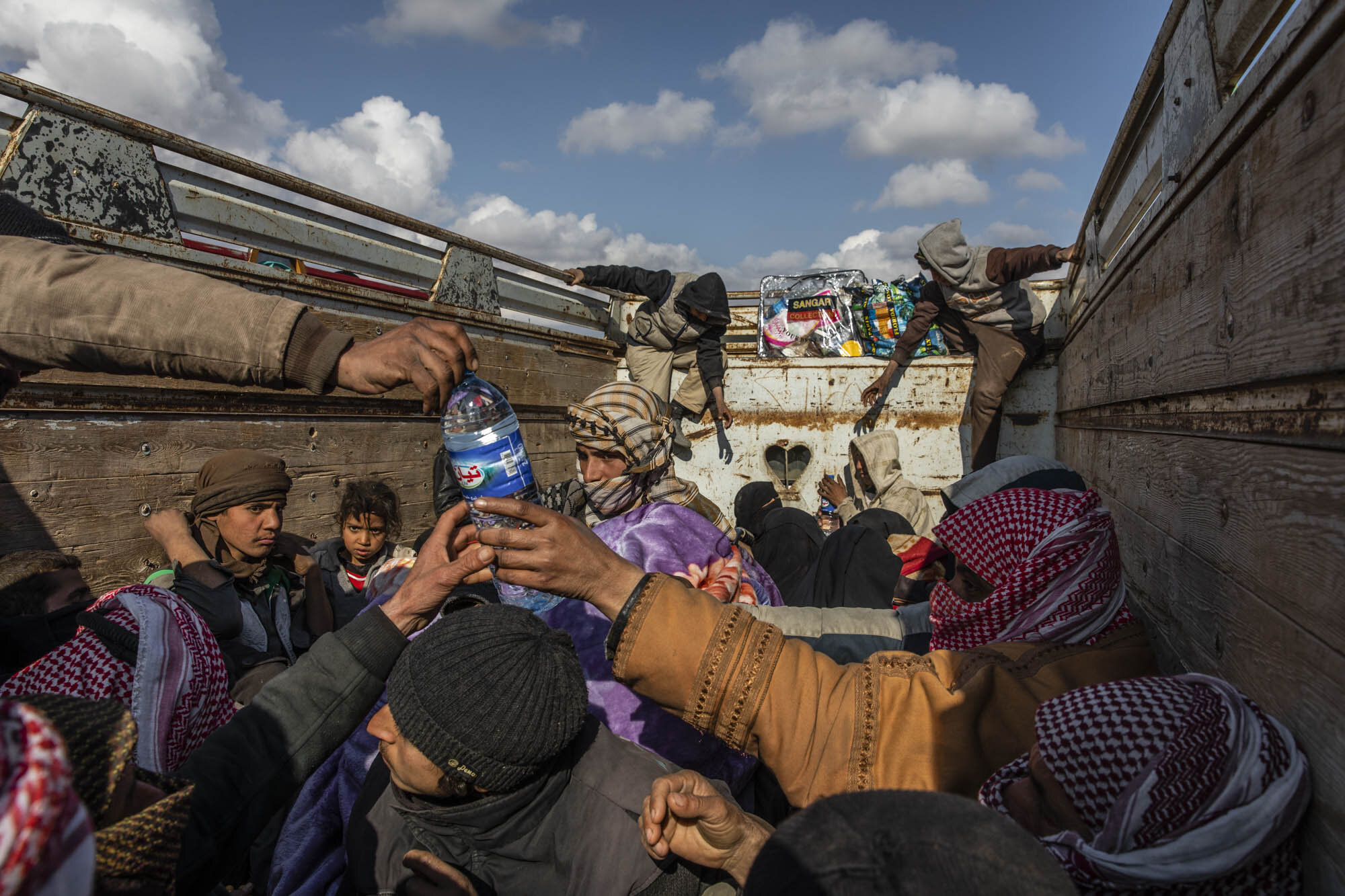  A convoy of trucks carrying hundreds of exhausted, dust covered people, many of them Syrian and Iraqi civilians, who had been evacuated from the last remaining patch of ISIS territory, stopped on the way to secure detention camps further north. 