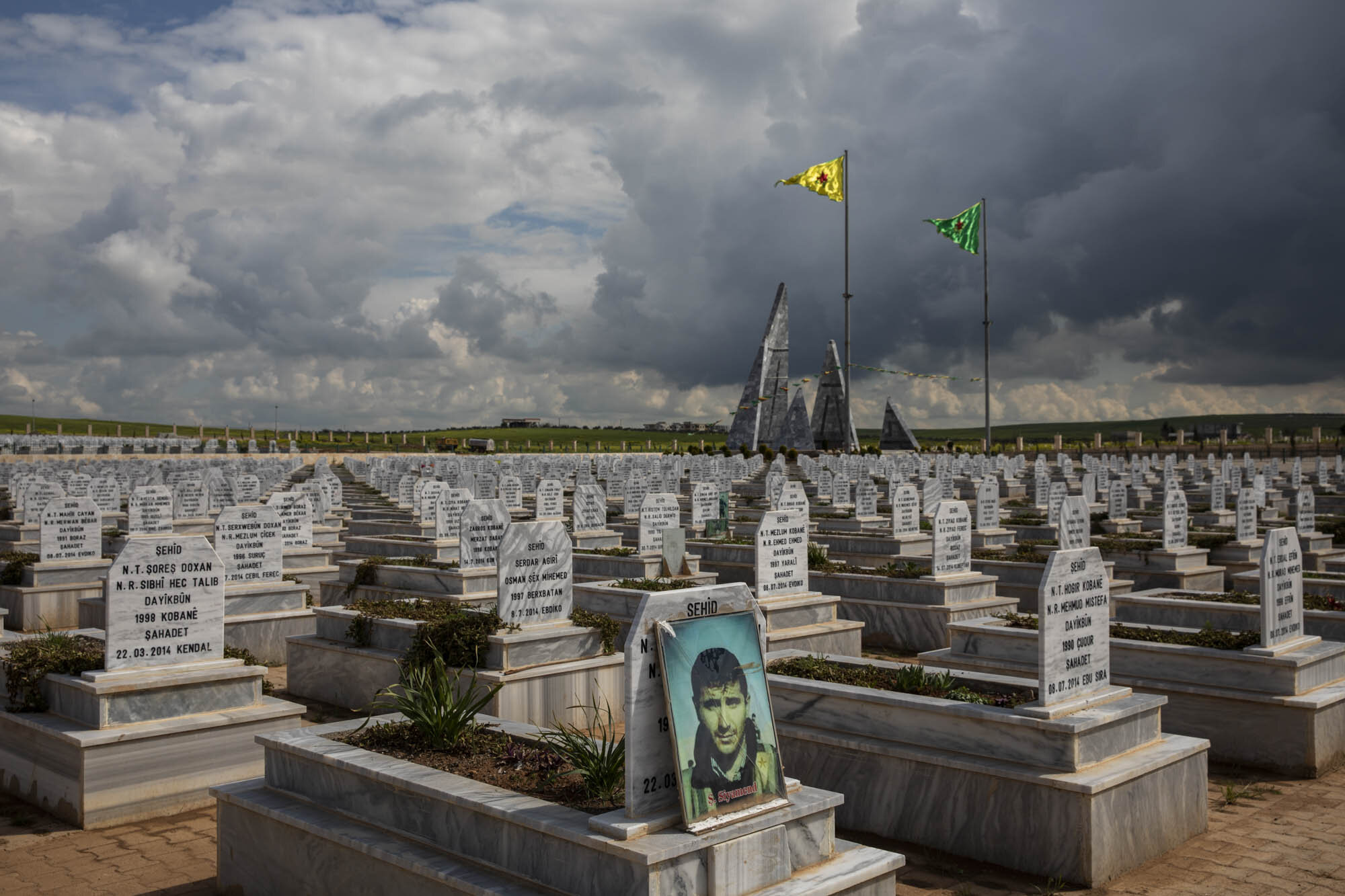  A portrait of a martyred Kurdish fighter, who died during the fight against ISIS, sat amidst a sea of graves at the martyrs cemetery in Kobani, northern Syria. The US backed Syrian democratic forces released a statement claiming that they had lost m