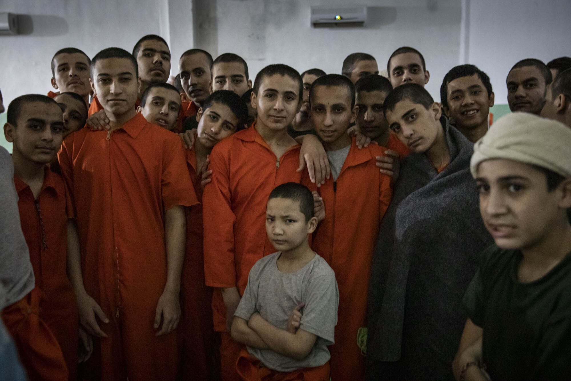Young boys of various ethnicities, stood for a picture in the crowded, dark cell where they were being held at a prison for suspected ISIS members in north east Syria.