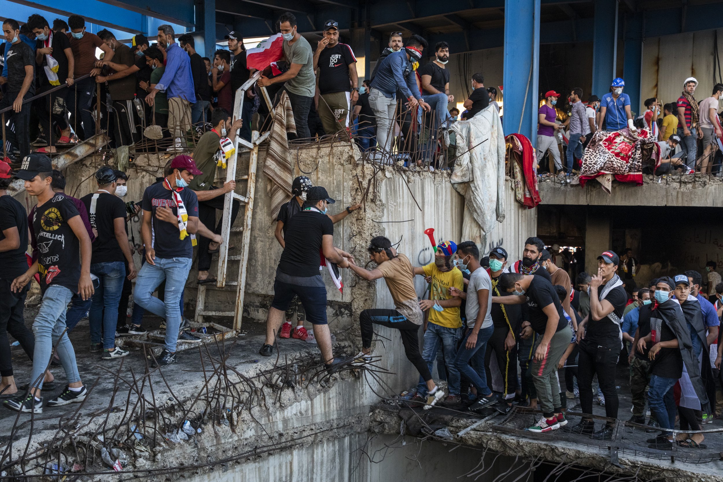  Young men tried to reach the upper levels of an unfinished building overlooking mass protests in Tahrir Square in Baghdad.  