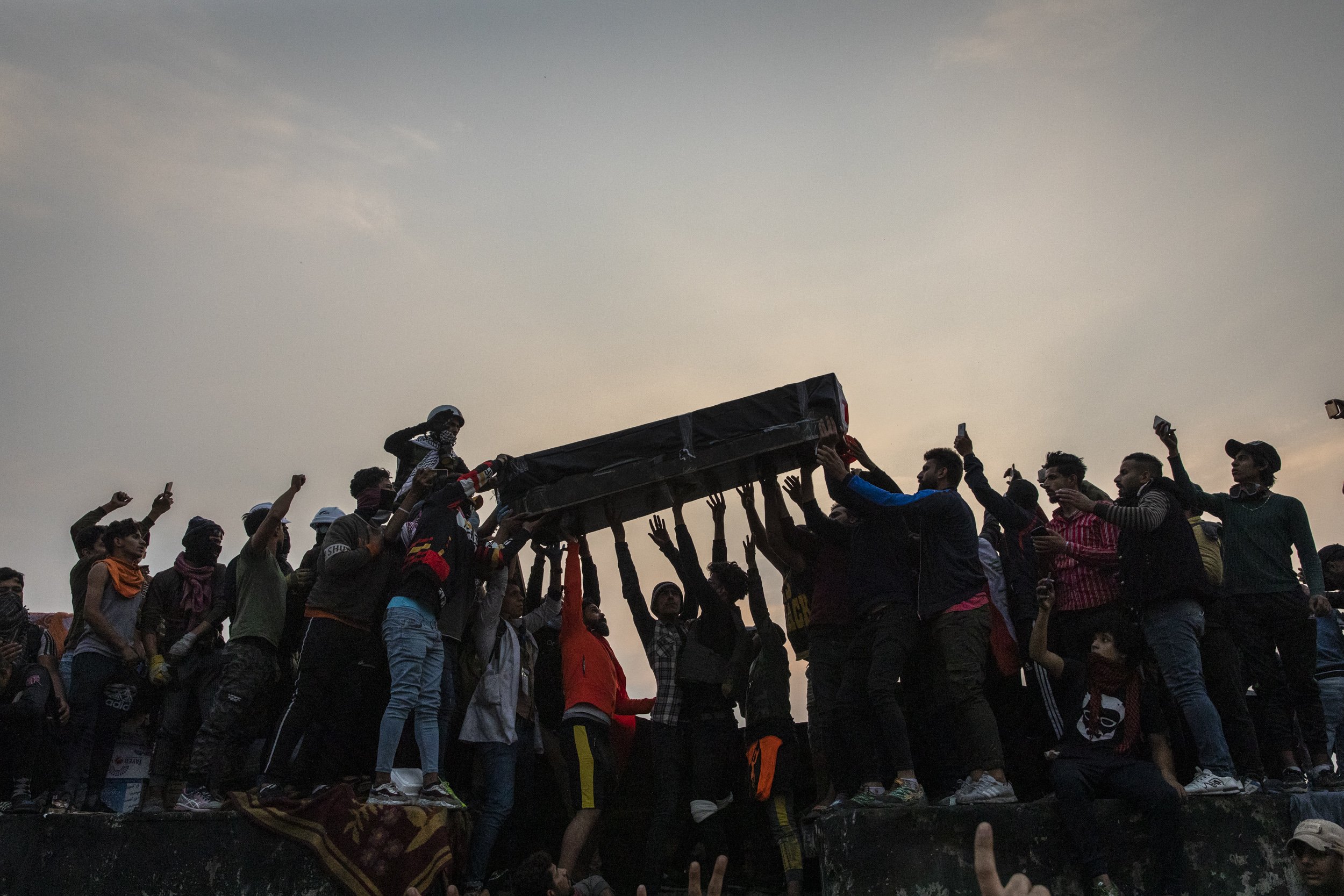  Friends and family members raise the coffin of 16-year-old Hussein Abid, who was killed by Iraqi security forces yesterday on Rasheed Street, atop a barricade on Ahrar bridge in Baghdad. 