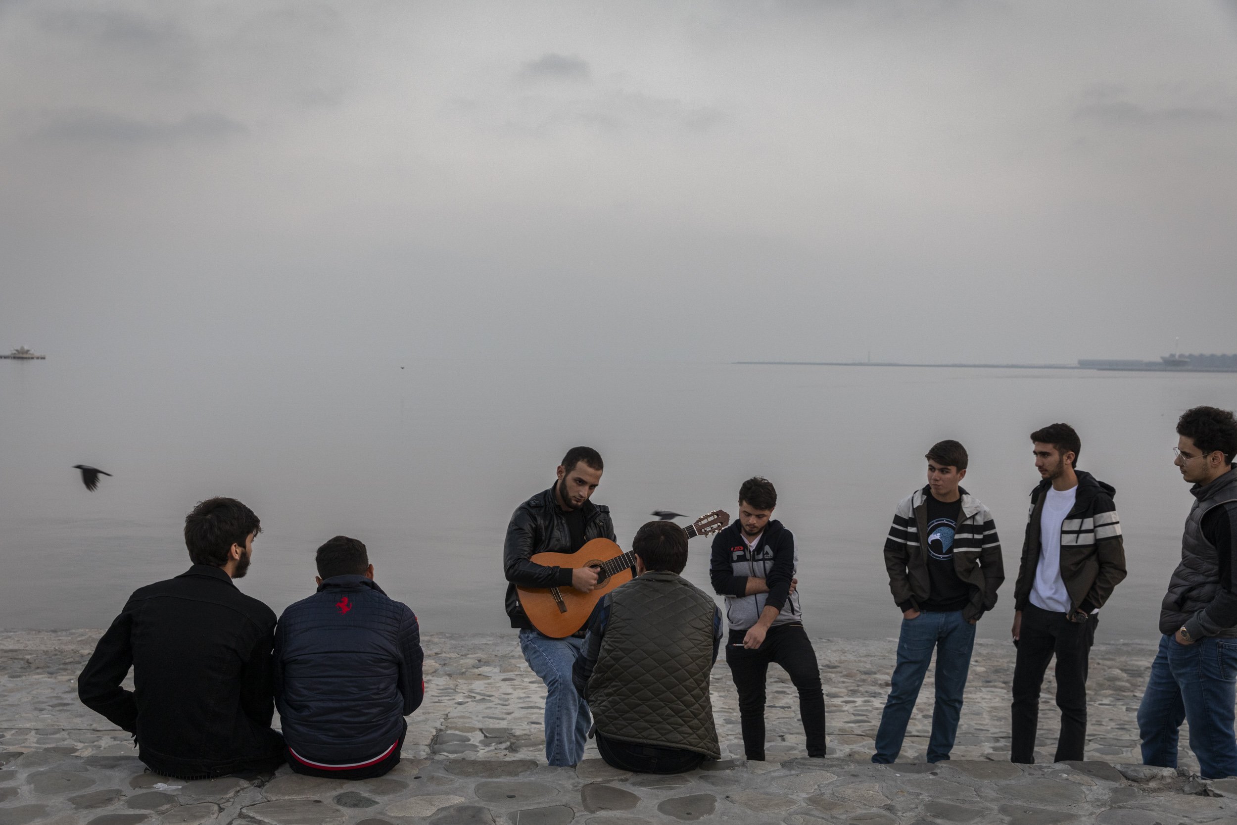  A young man played a guitar and sang while friends looked on along Baku Boulevard on the banks of the Caspian Sea in Baku. 