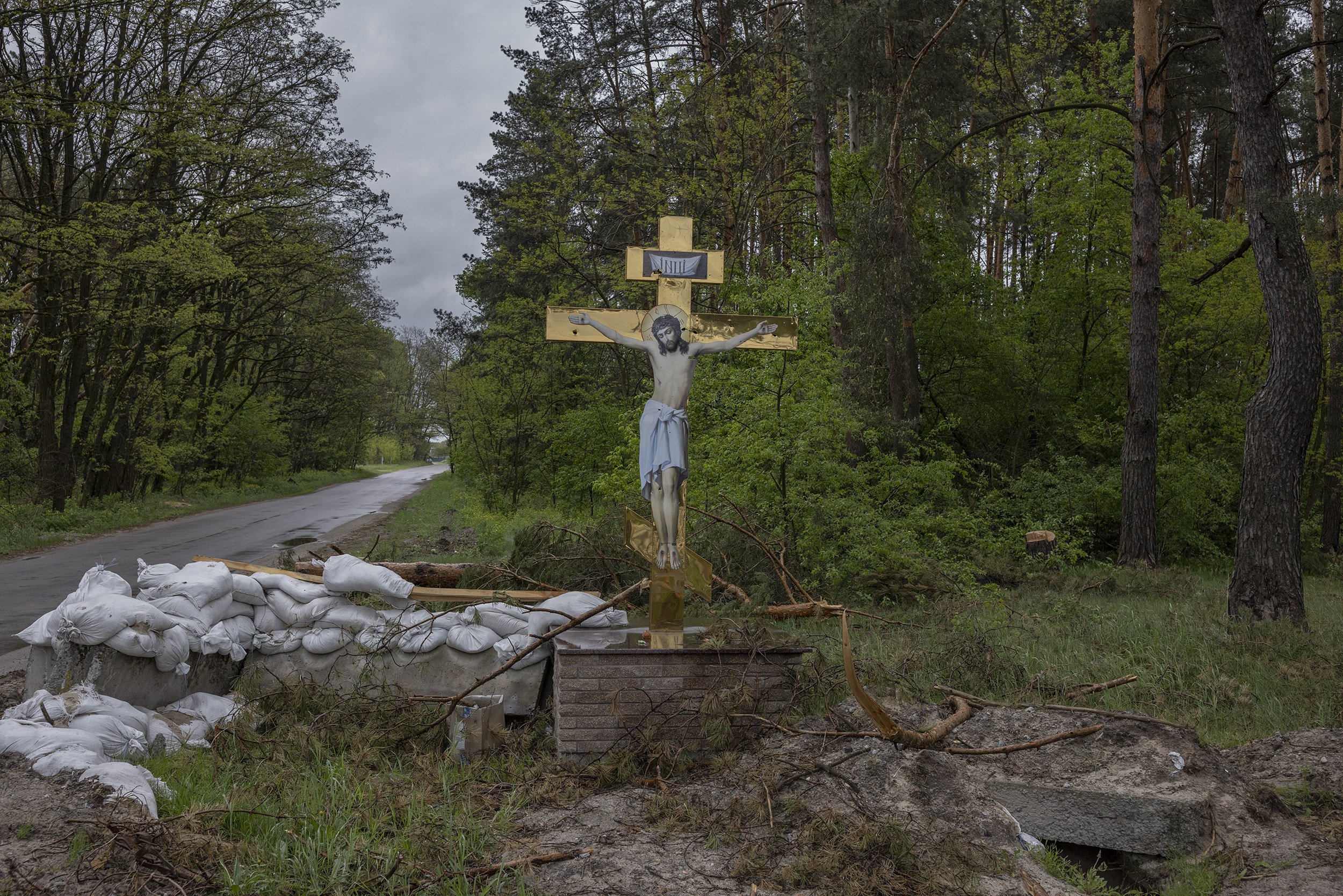  A statue of Jesus on the cross stood, riddled with bullet holes, beside a former Ukrainian checkpoint on the outskirts of the village of Bohdanivka, just north of Brovary, an eastern suburb of Kyiv. May, 2022. 