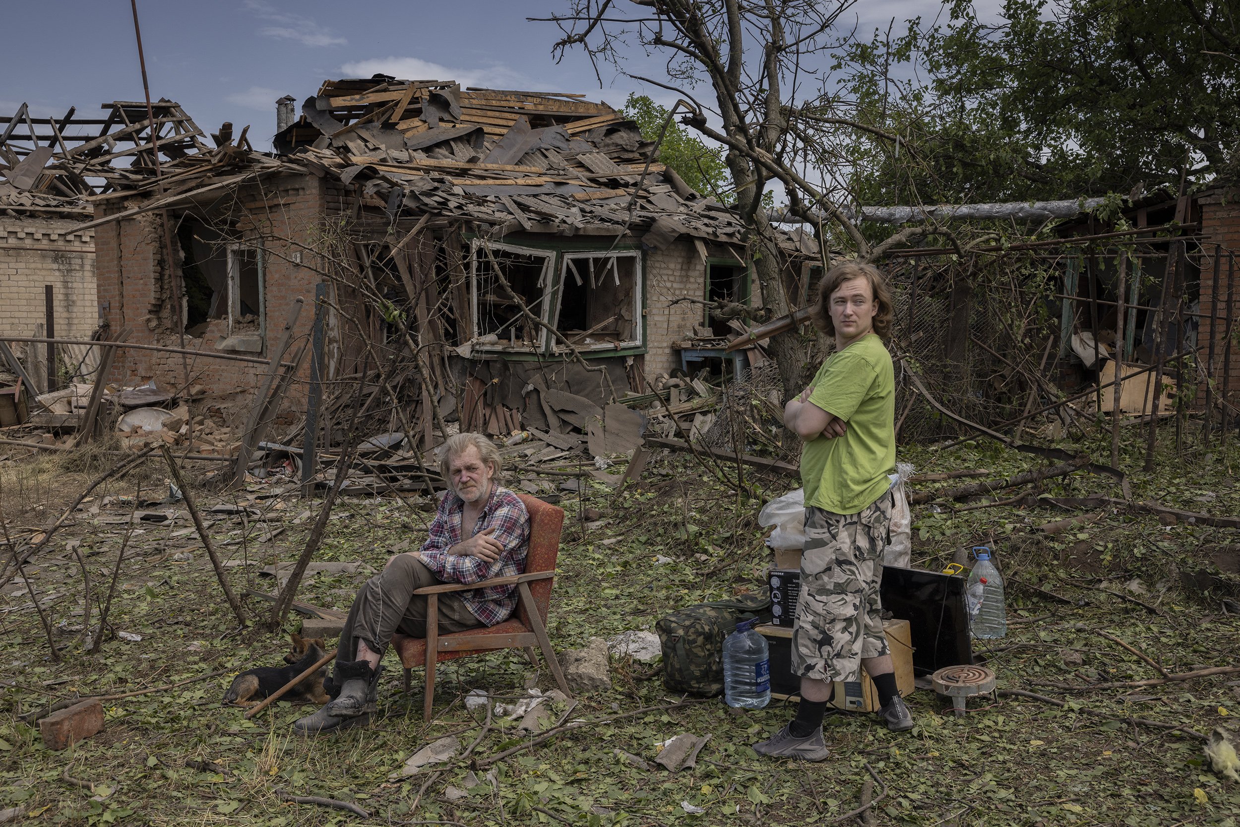  Mykola Holovko and his son sat in front of their destroyed home, having salvaged what they could from the wreckage after a Russian missile landed across the street during the night. June, 2022. 