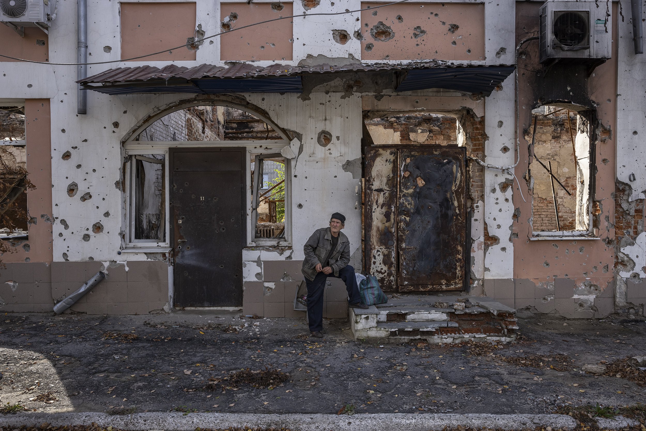  A man stood in front of a heavily destroyed building after collecting humanitarian aid in the recently liberated city of Izium in Ukraine’s east. Russian forces were routed from the area after more than six months of occupation. October, 2022. 