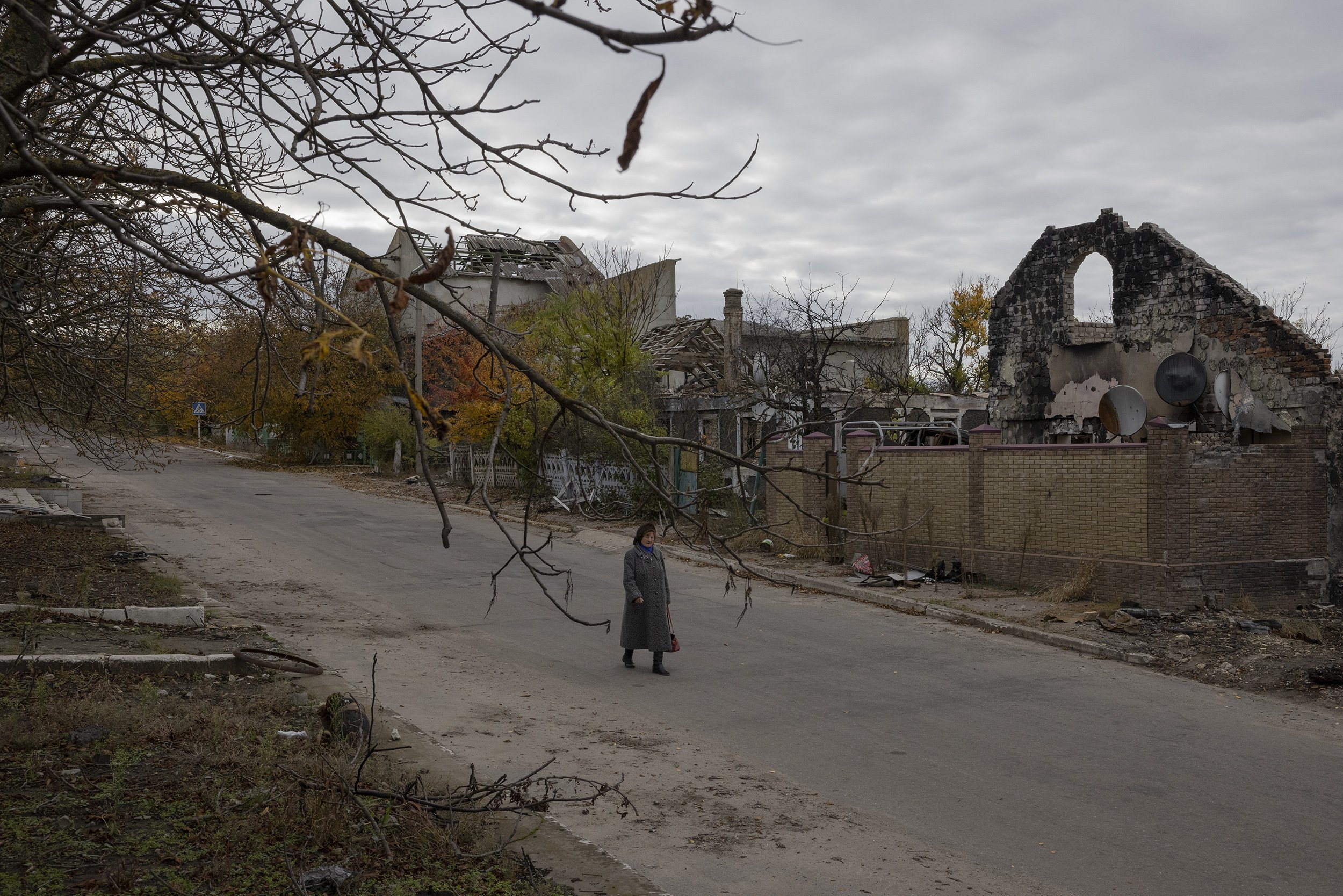  A woman walked past destroyed houses in the town of Velyka Oleksandrivka, that was liberated from Russian control earlier that month. October, 2022. 