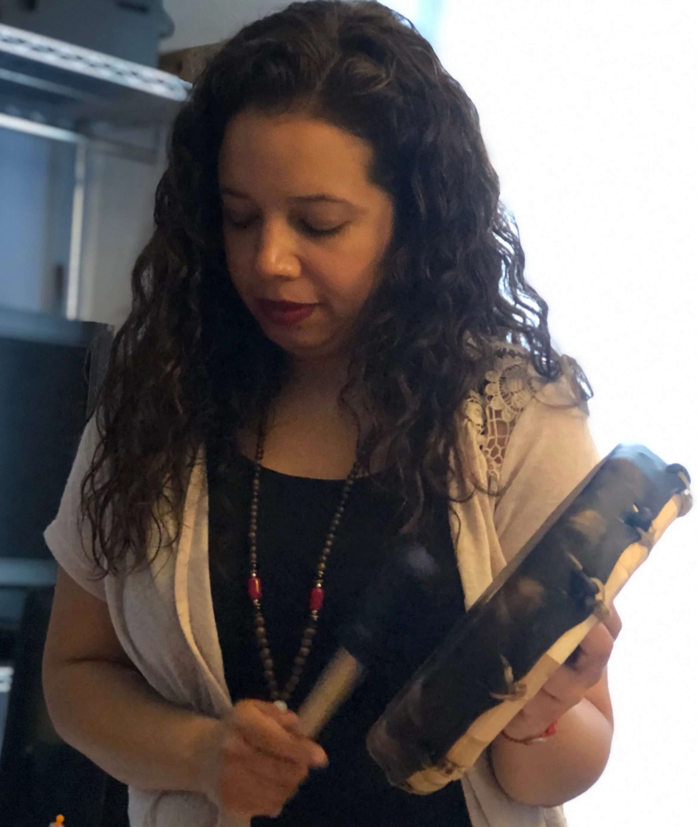 Awilda Alvarez holding a drum looking down with long black curly hair