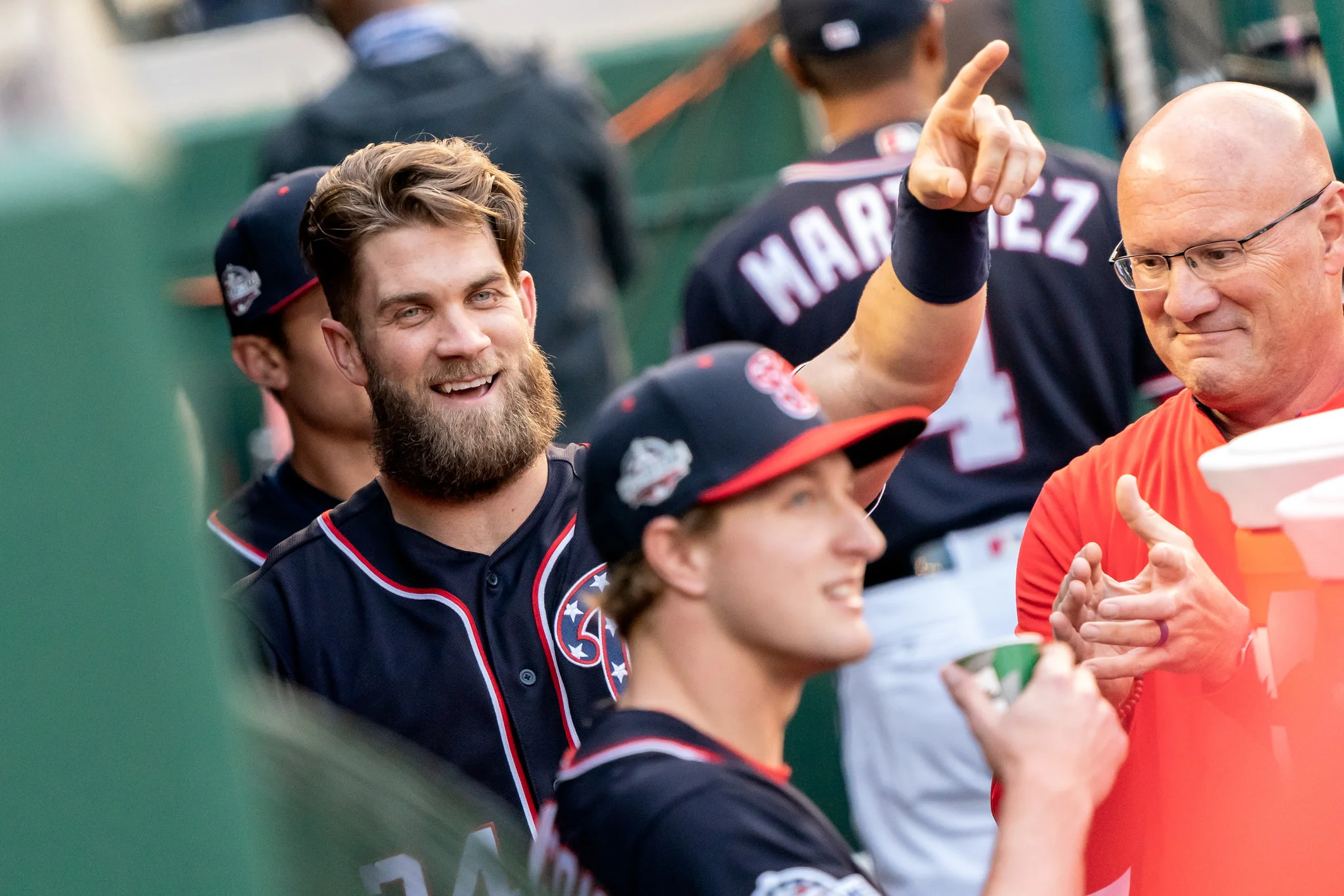 Bryce Harper points to the scoreboard from the dugout when Andrew Stevenson is announced at the beginning of the game, Washington Nationals Park