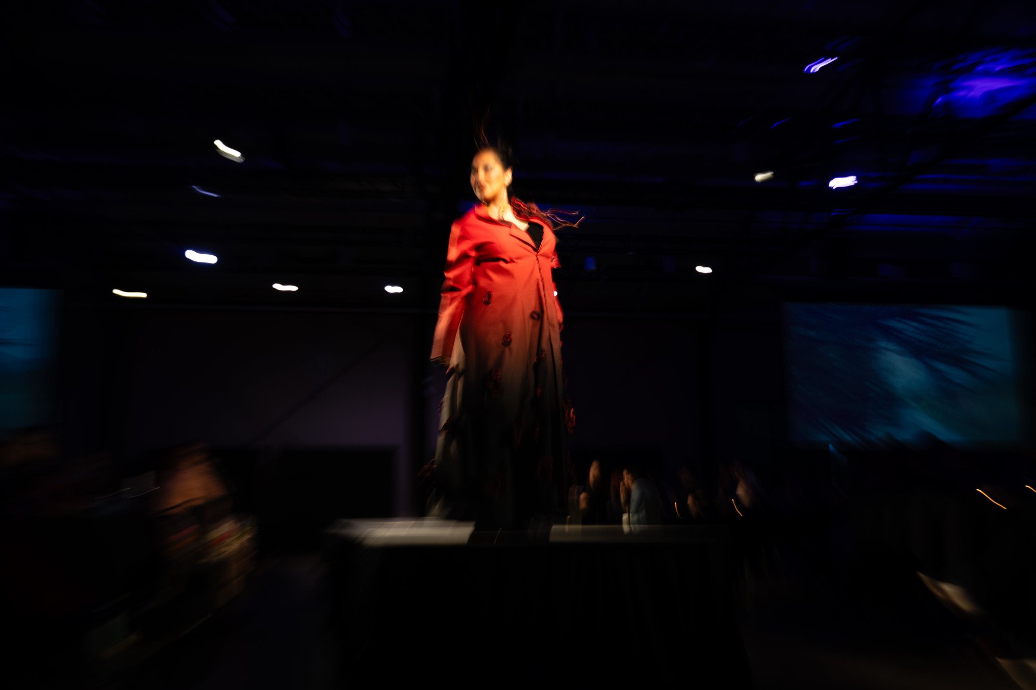 Motion blur of a model wearing a piece by The Restorative Apparel Co-Design Collection on the runway at Native Nations Fashion Night in Minneapolis