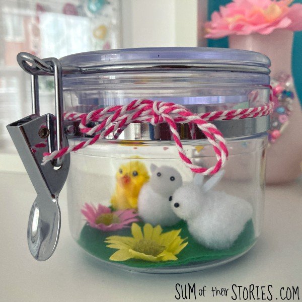 a jar with a spring scene made from bunny and chick cake decorations