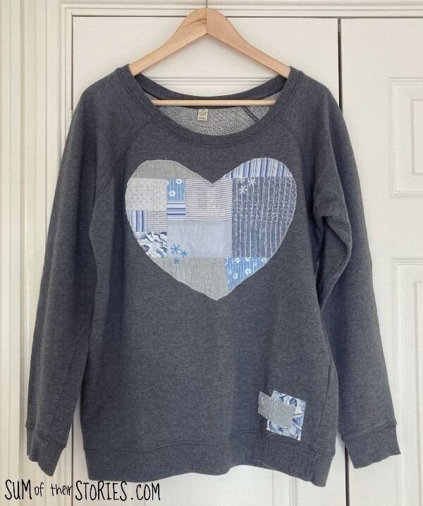 A grey sweatshirt with a patchwork heart applique