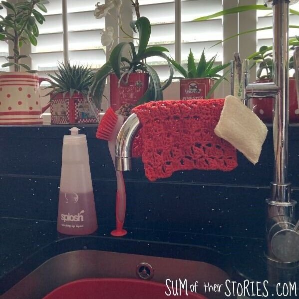 A red handmade dishcloth hanging by a kitchen sink