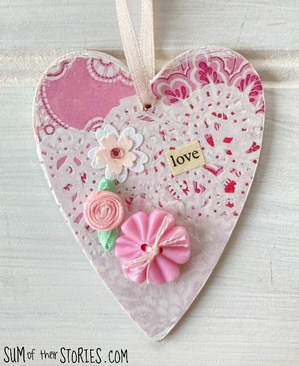 wooden heart covered in pink paper with button and flower embelishment