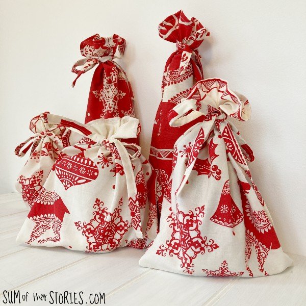 A collection of red and white Christmas gift bags made from fabric with a tie top