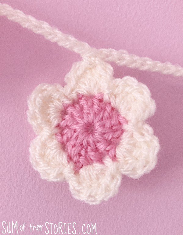 a pink and white crochet flower on a pink background