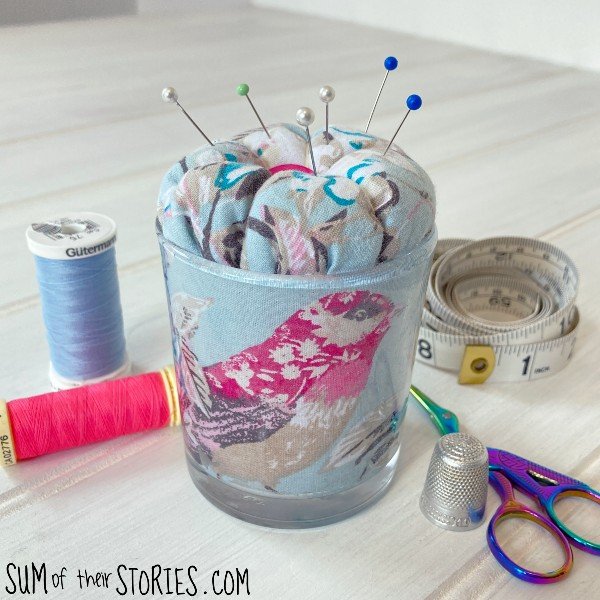 A pin cushion made from a light blue fabric with a bird print