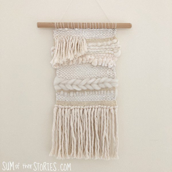 A woven wall hanging in cream and white textured yarn