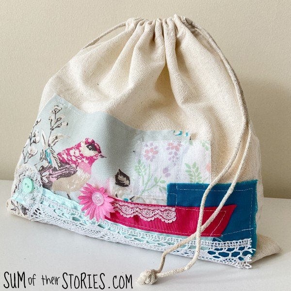 A natural linen drawstring bag decorated with scraps of fabric, ribbon and lace