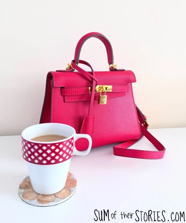  red leather kelly style handbag next to a cup of tea. the bag is made from a kit 