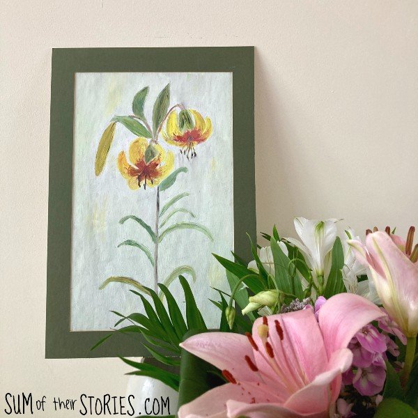 A painting of a lily propped up behind a bunch of pretty flowers