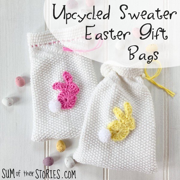 2 gift bags made from old sweater sleeves with rabbit crochet embellishments, surrounded by mini eggs