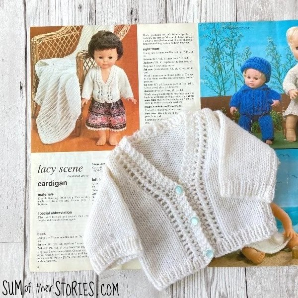 white knitted doll cardigan on top of the pattern