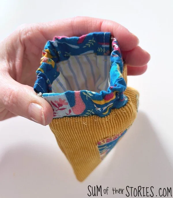 a small fabric pouch made with a flex frame closure squeezed to show how it opens