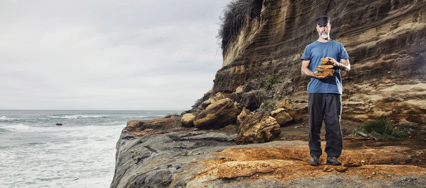 Scott Sutton holds a stack of red ochre slabs on Oregon’s coast. Photo by Buck the Cubicle.