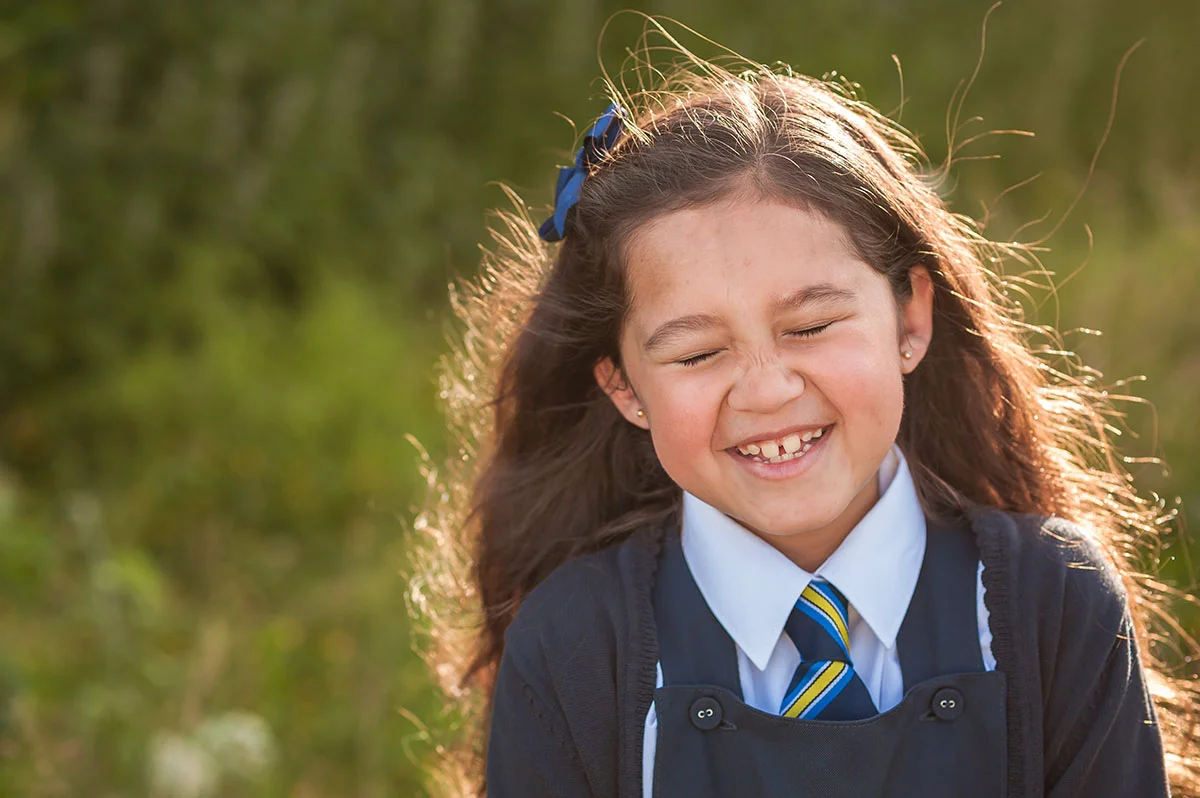 Little girl giggling in school uniform (1).jpg