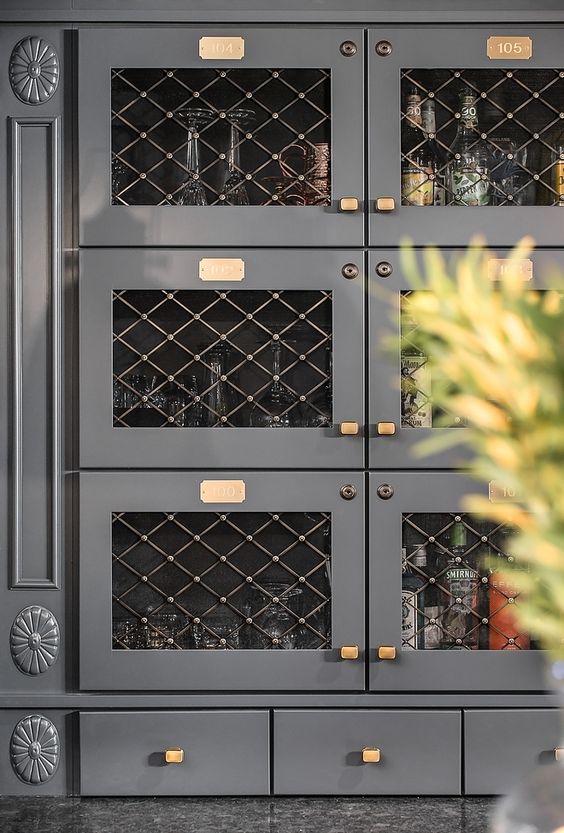dark gray cabinets with brass hardware and wire mesh insert