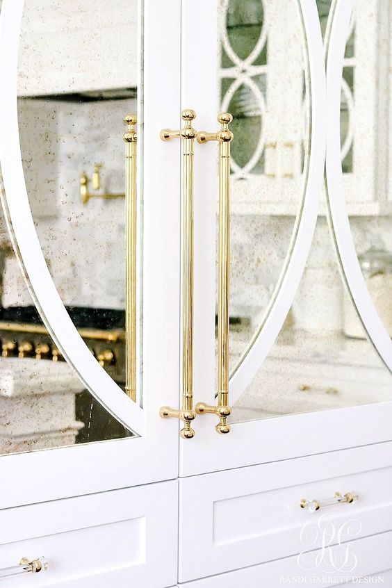 white cabinets with antiqued mirror and decorative mullion inserts with unlacquered brass hardware