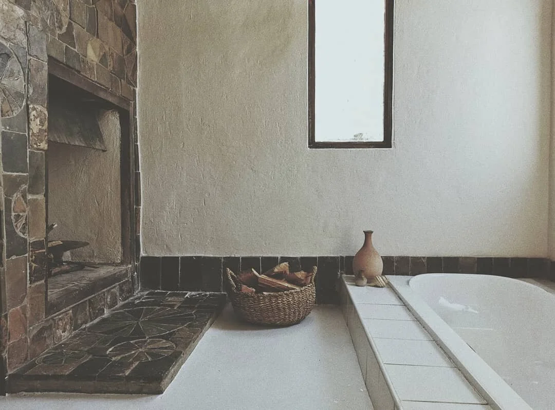 plaster wall bathroom fireplace fieldstone inset bathtub abode