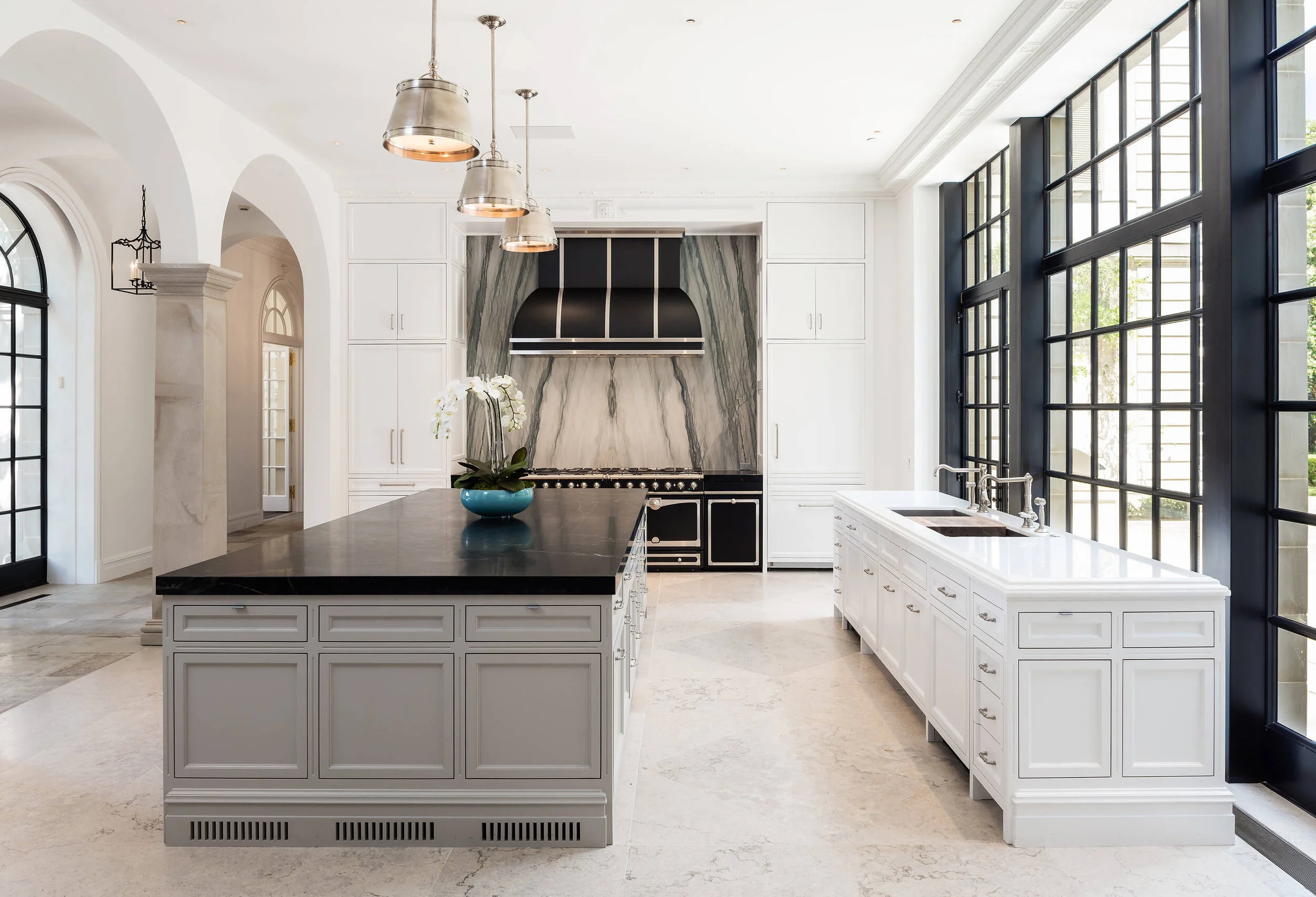 transitional kitchen two tone marble nero marquina carrara bookmatched marble la cornue grid door marble floor pendants
