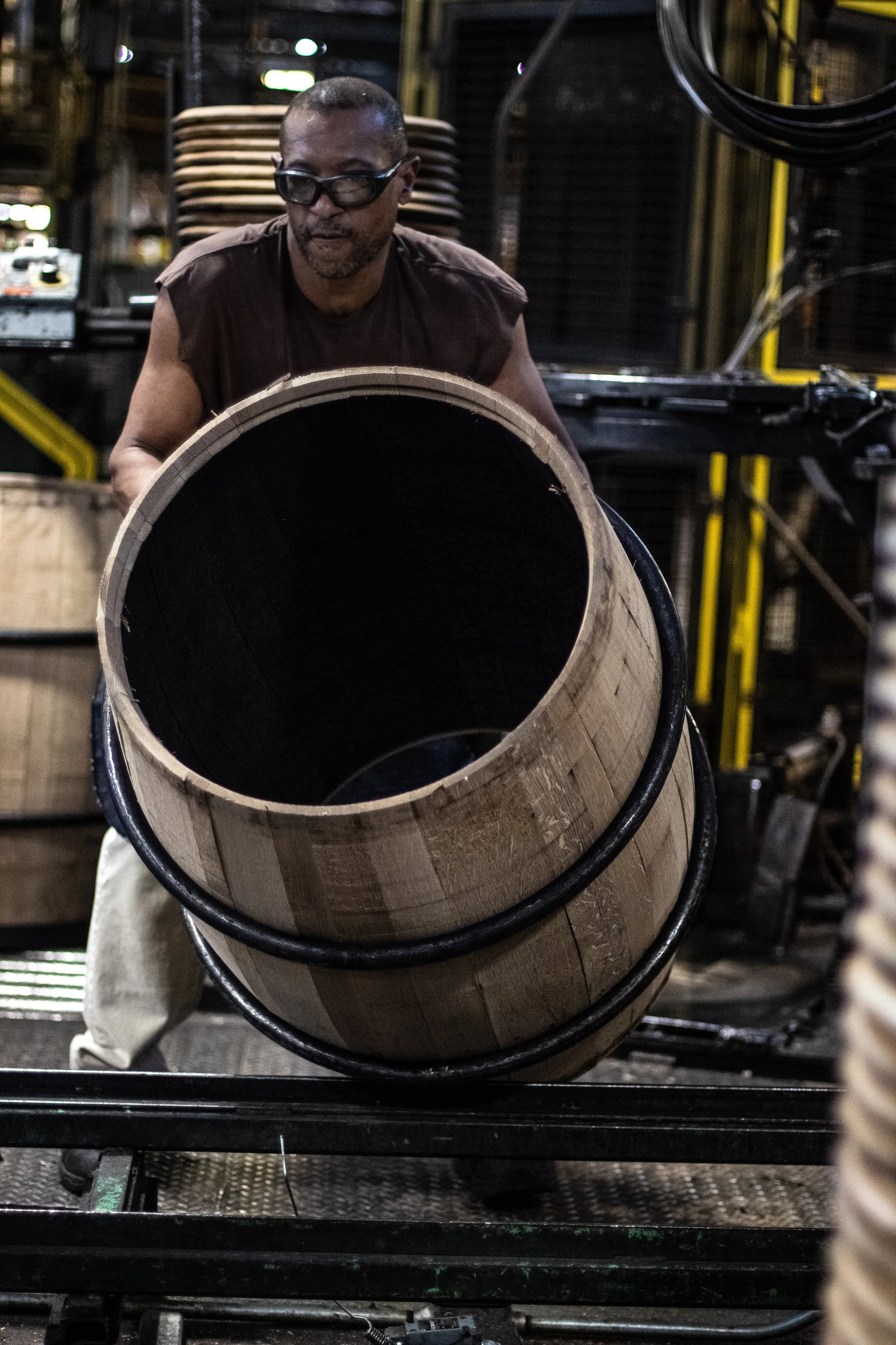 A worker, rolling a recently charred barrel to its next station.