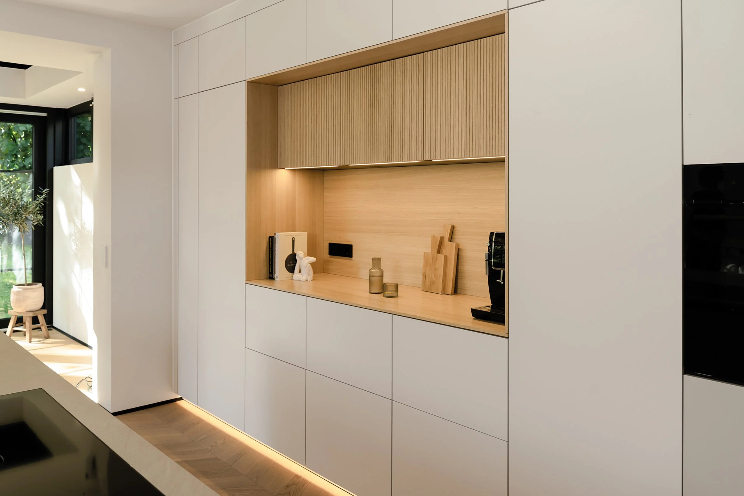 Symmetrical tall bank of next125 matt slab kitchen units with oak veneered wall doors