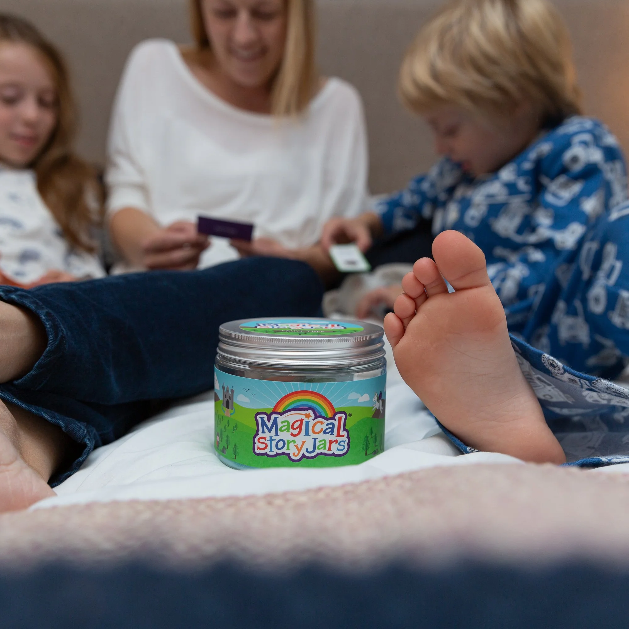 Mum and young son sitting on a bed together making up a bedtime story using a Magical Story Jar storytelling kit
