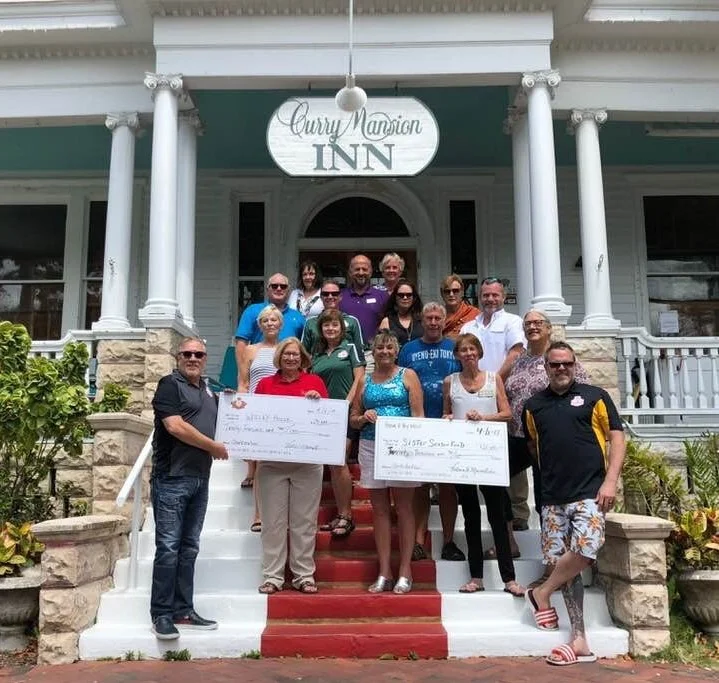 ABOVE: KREWE PRESENTS CHECKS TO SISTER SEASON FUND & WESLEY HOUSE FROM DONATIONS THAT WERE RAISED BY THE 2018 BLUE TARP FASHION SHOW. A BIG THANK YOU TO PHIL AND NANCY AMSTERDAM FOR PROVIDING THE LOVELY SETTING AND TO THE FASHION SHOW COMMITTEE. BELOW: KREWE PRESENTS 2019 FASHION SHOW PROCEEDS TO SISTER SEASON FUND AND WOMANKIND.