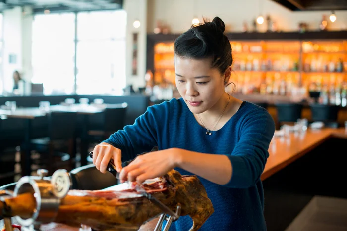 Tracy artfully cuts a leg of jamón, Spanish ham that is a staple on Pagu’s menu. Photograph by Lydia Carmichael/The Thirty-One Percent